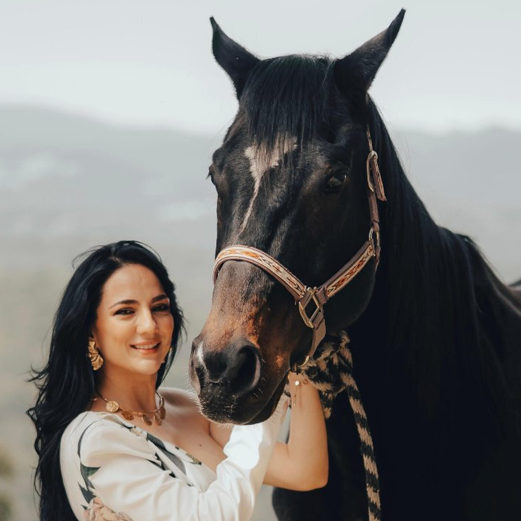 Karen Leal junto a un caballo negro